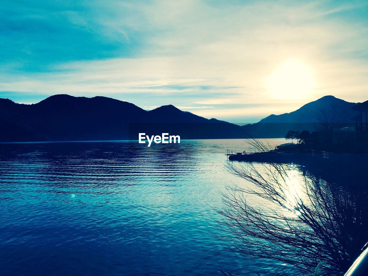 SCENIC VIEW OF SEA BY SILHOUETTE MOUNTAINS AGAINST SKY