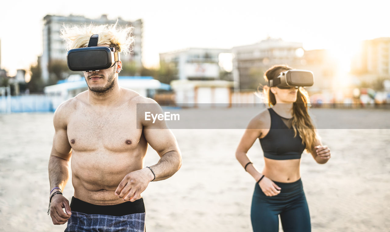 Couple wearing virtual reality simulator while standing at beach