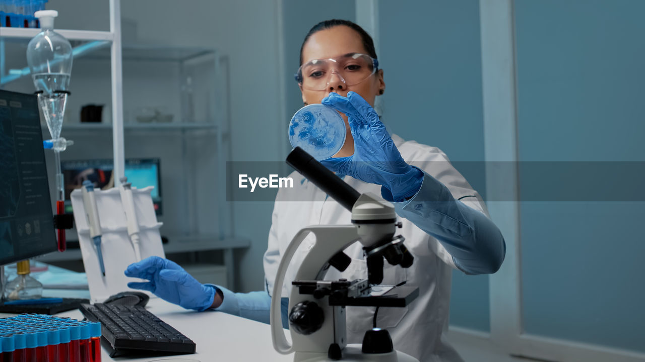 portrait of young woman using mobile phone while standing in laboratory