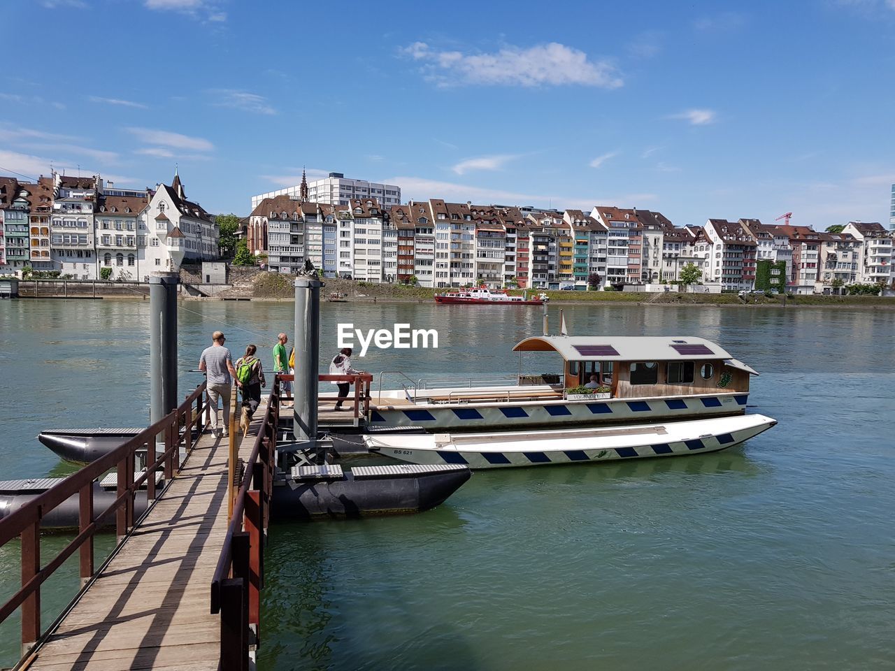 Boats in river by buildings in city against sky