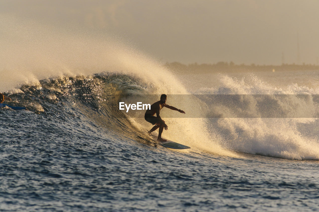 Mid adult man surfing on sea during sunset