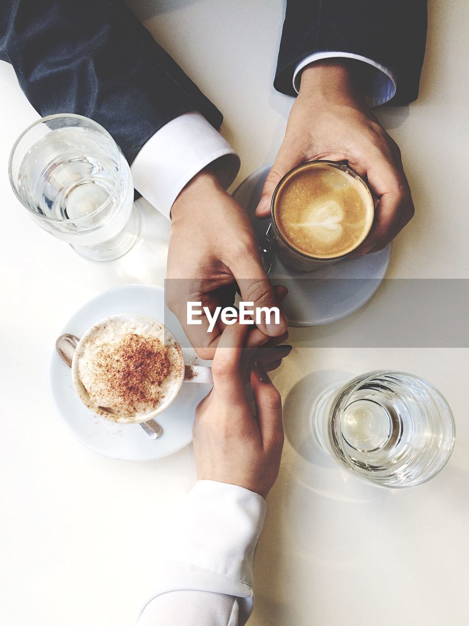 Directly above view of couple holding hands at coffee shop