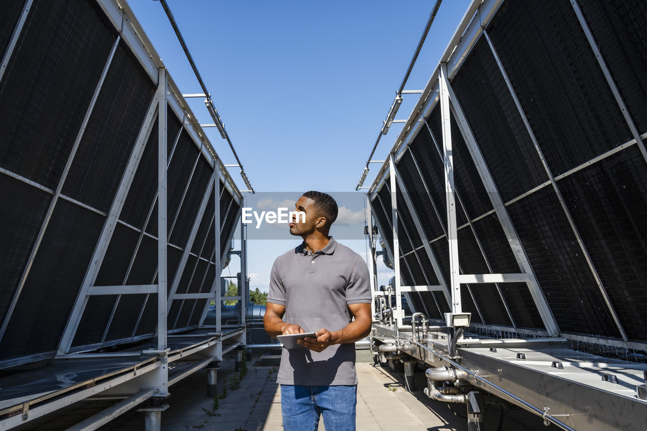 Employee with digital tablet checking refrigeration installation on rooftop