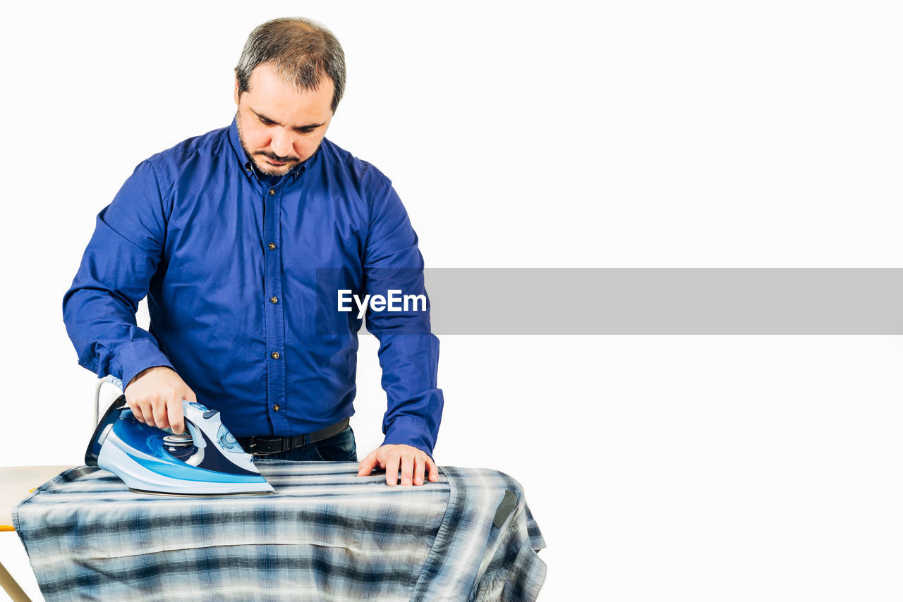 Man ironing clothes against white background