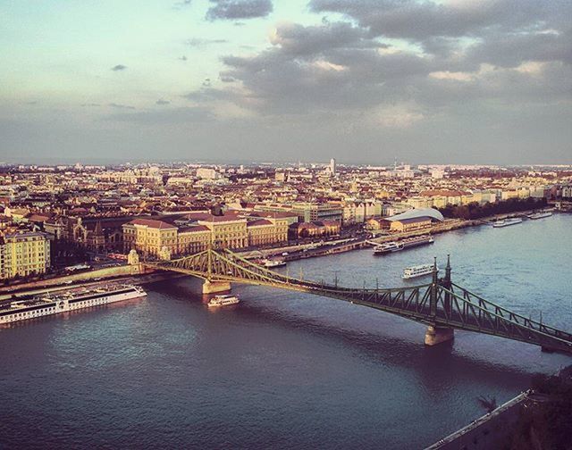 BRIDGE OVER RIVER WITH CITYSCAPE IN BACKGROUND