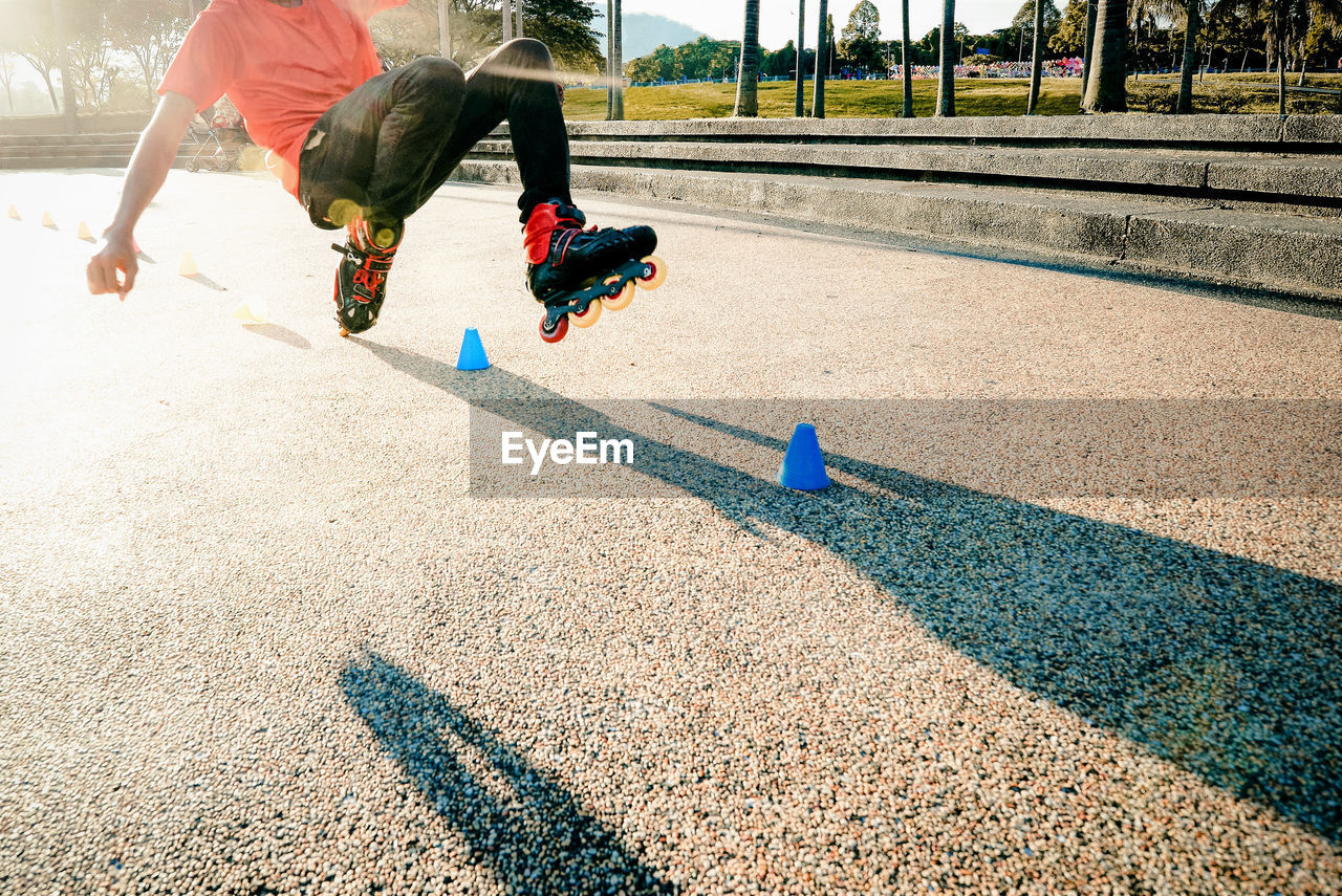 Low section of man inline-skating on road