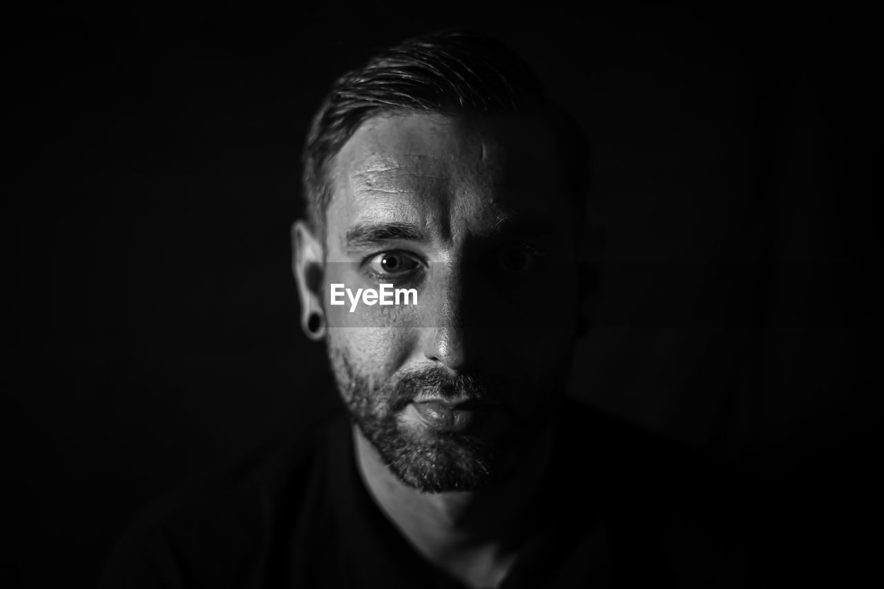 Close-up portrait of man against black background