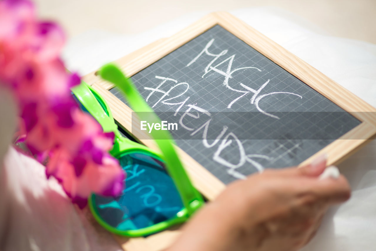 Cropped image of bride holding slate with text