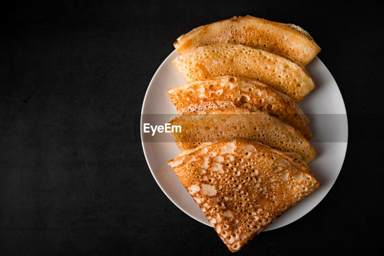 Tasty crepes on a plate on a black background. traditional russian food. place for your text.