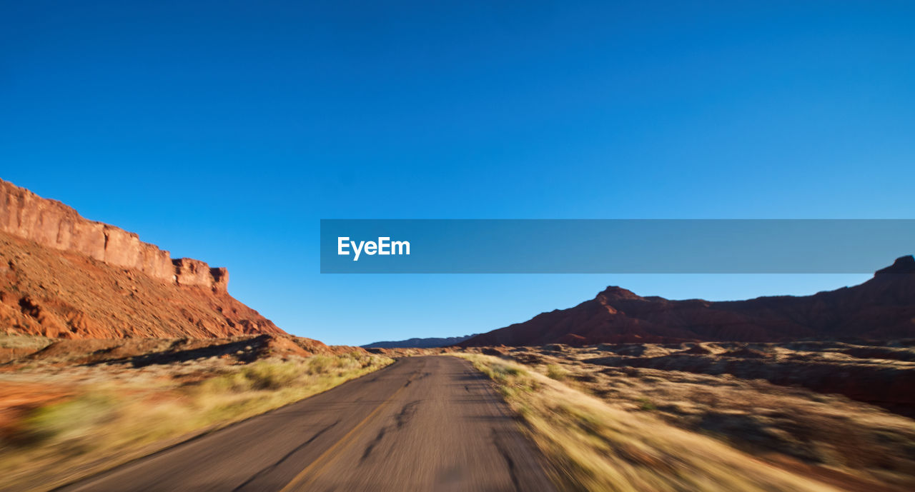 Road amidst mountains against clear blue sky