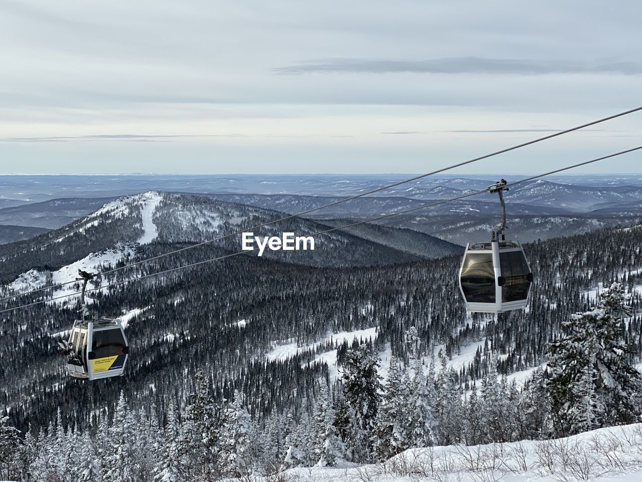 OVERHEAD CABLE CAR AGAINST SNOWCAPPED MOUNTAINS DURING WINTER