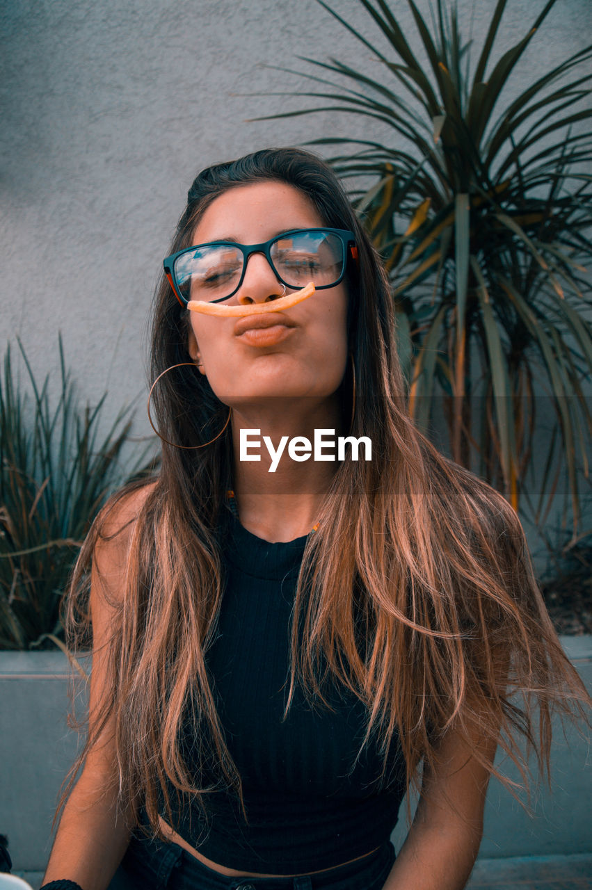 PORTRAIT OF SMILING YOUNG WOMAN WEARING EYEGLASSES