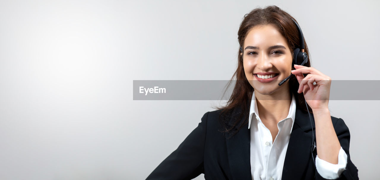 PORTRAIT OF SMILING YOUNG WOMAN USING MOBILE PHONE