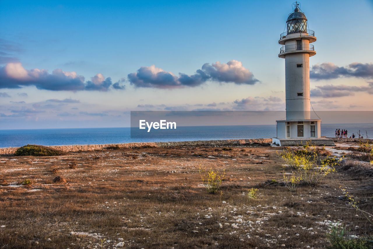 Lighthouse by sea against sky