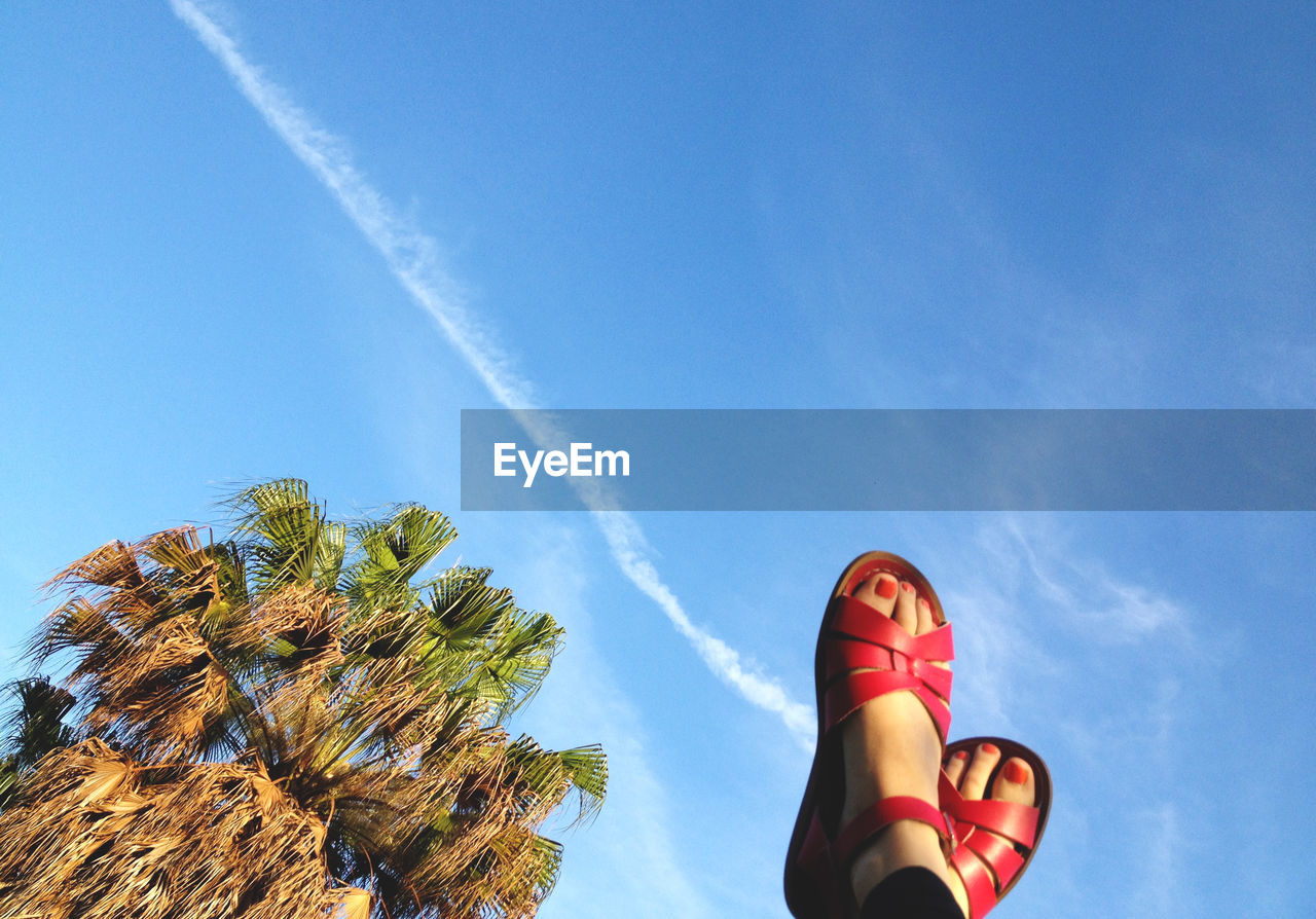 Low angle view of woman with feet up against sky