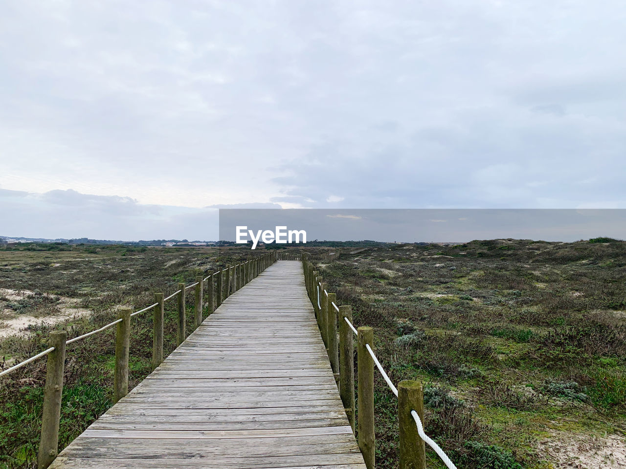 the way forward, sky, cloud, nature, landscape, footpath, environment, scenics - nature, land, boardwalk, beauty in nature, tranquility, tranquil scene, wood, non-urban scene, railing, no people, plant, walkway, diminishing perspective, day, footbridge, outdoors, architecture, vanishing point, sea, bridge, coast, grass, built structure, horizon, idyllic, hill, remote, rural area, water, travel destinations, field, travel, rural scene, horizon over land