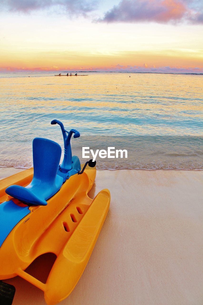 Boat on shore at beach against sky during sunset