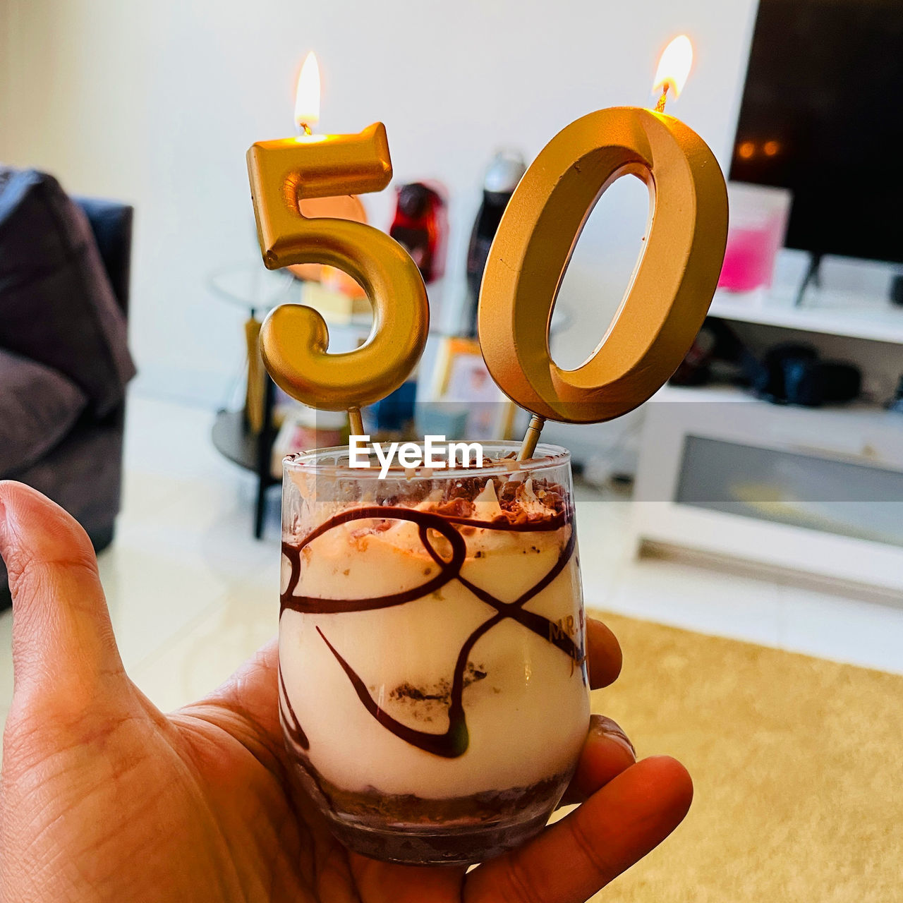 hand, one person, holding, indoors, food and drink, food, dessert, candle, adult, yellow, lifestyles, art, business, cake, cartoon, focus on foreground, table