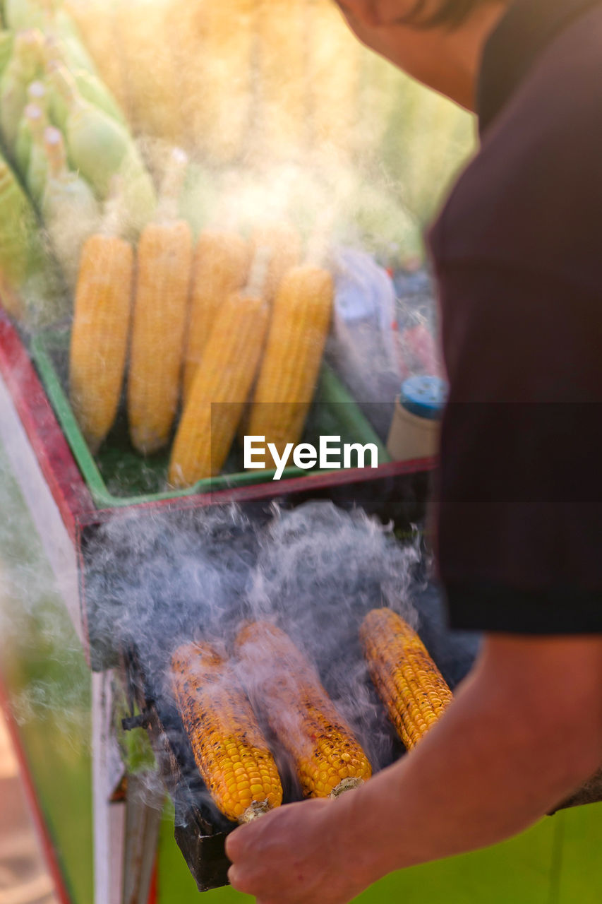 Midsection of man preparing corn