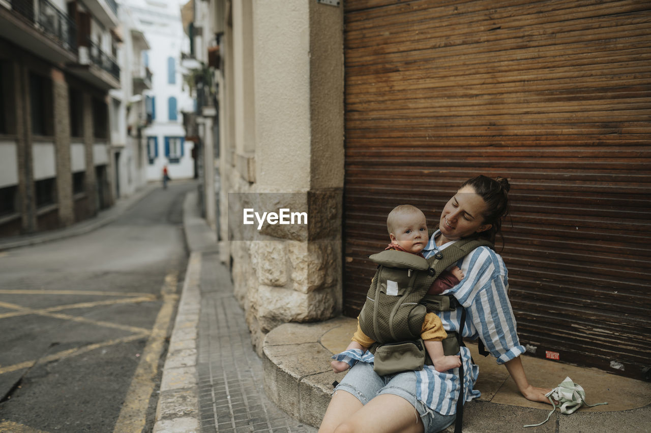 Mother with baby sitting on street