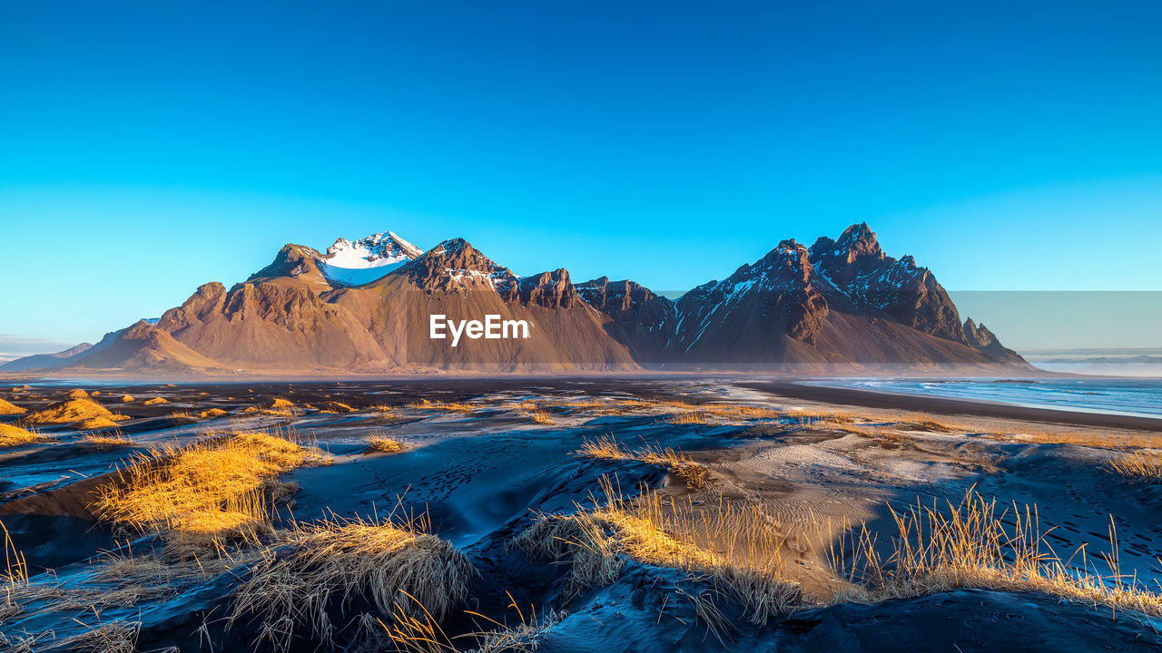 Scenic view of snowcapped mountains against clear blue sky