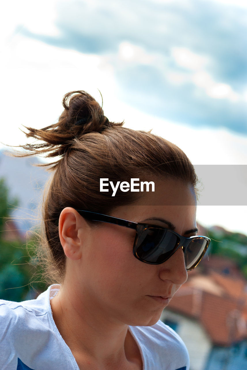 Close-up of woman wearing sunglasses while looking away against sky