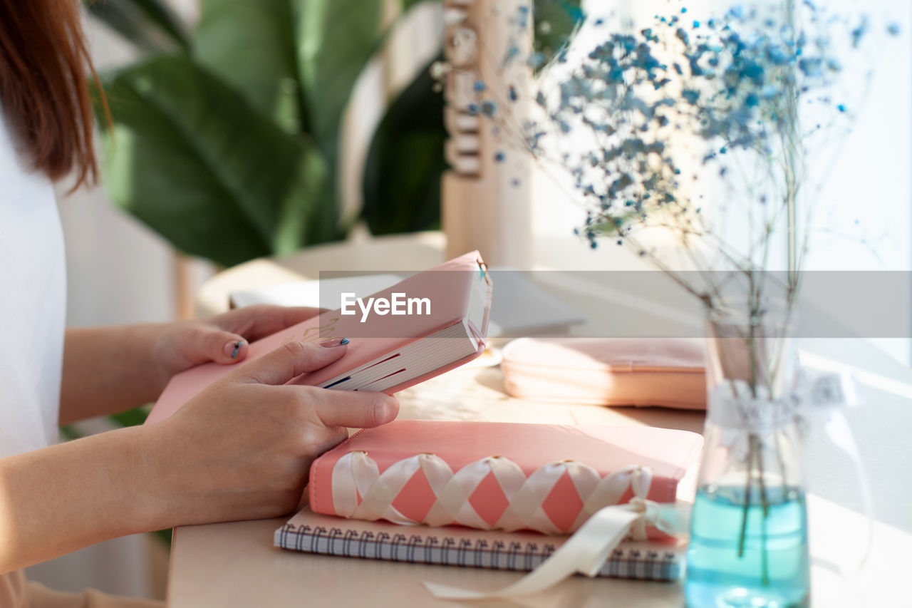 Midsection of woman holding smart phone on table