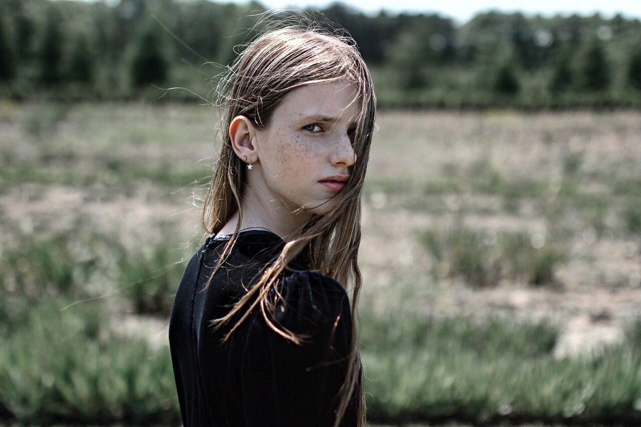 YOUNG WOMAN STANDING IN FIELD