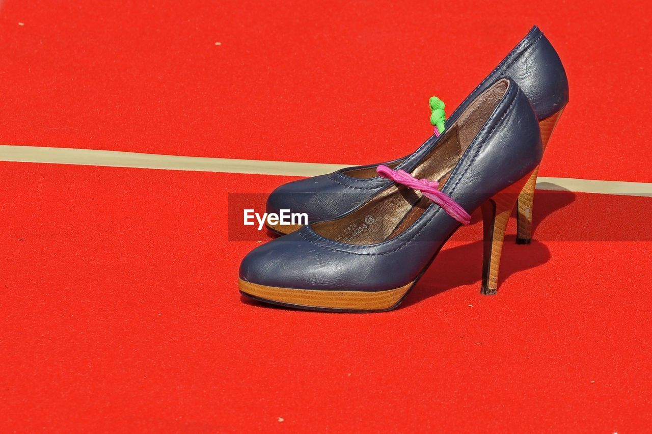 HIGH ANGLE VIEW OF SHOES ON RED SURFACE