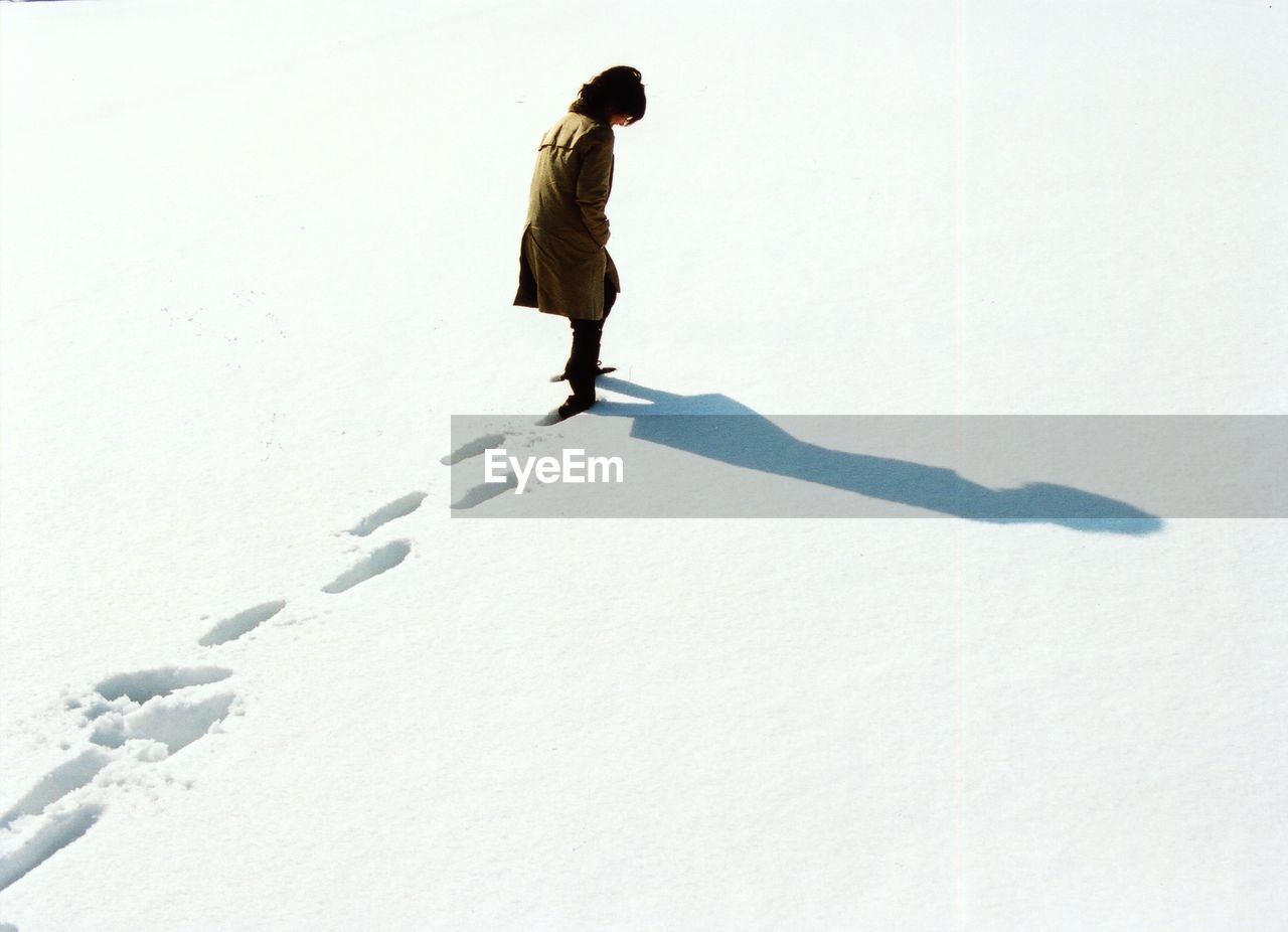 High angle view of woman walking in snow leaving behind footprints