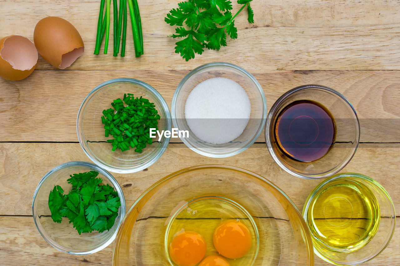 Directly above shot of egg yolks surrounded with various ingredients on table