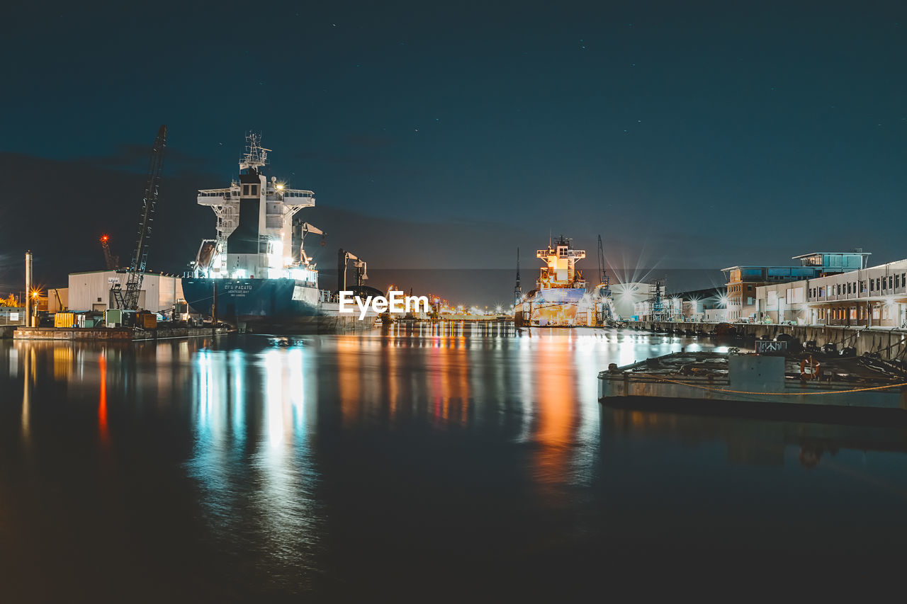 ILLUMINATED SHIP MOORED AT HARBOR AGAINST SKY