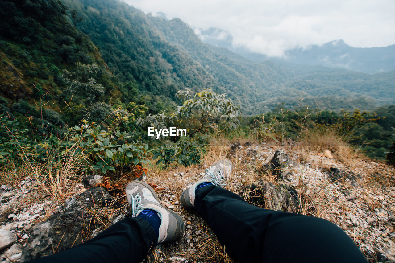 Low section of person wearing shoes sitting on cliff