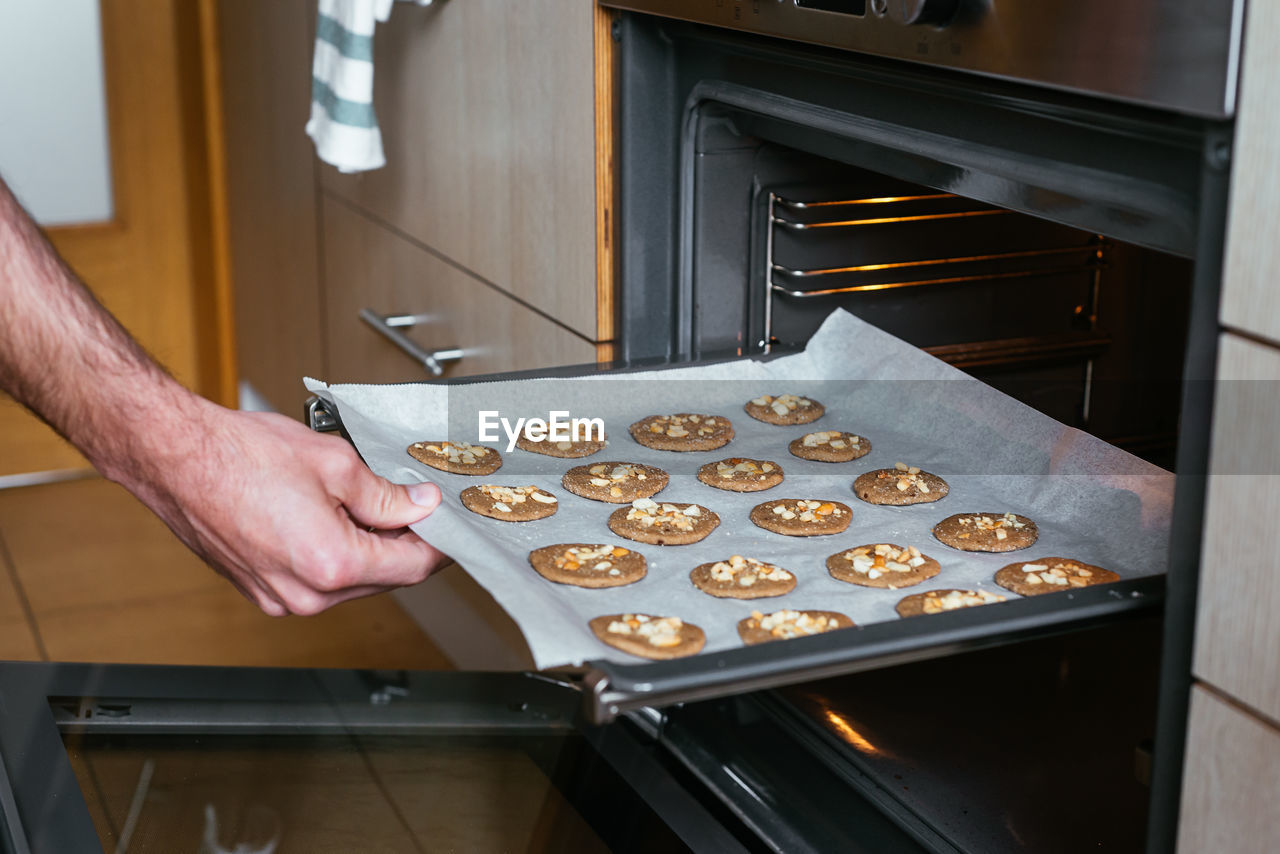 Young man putting the home-made cookies in the oven