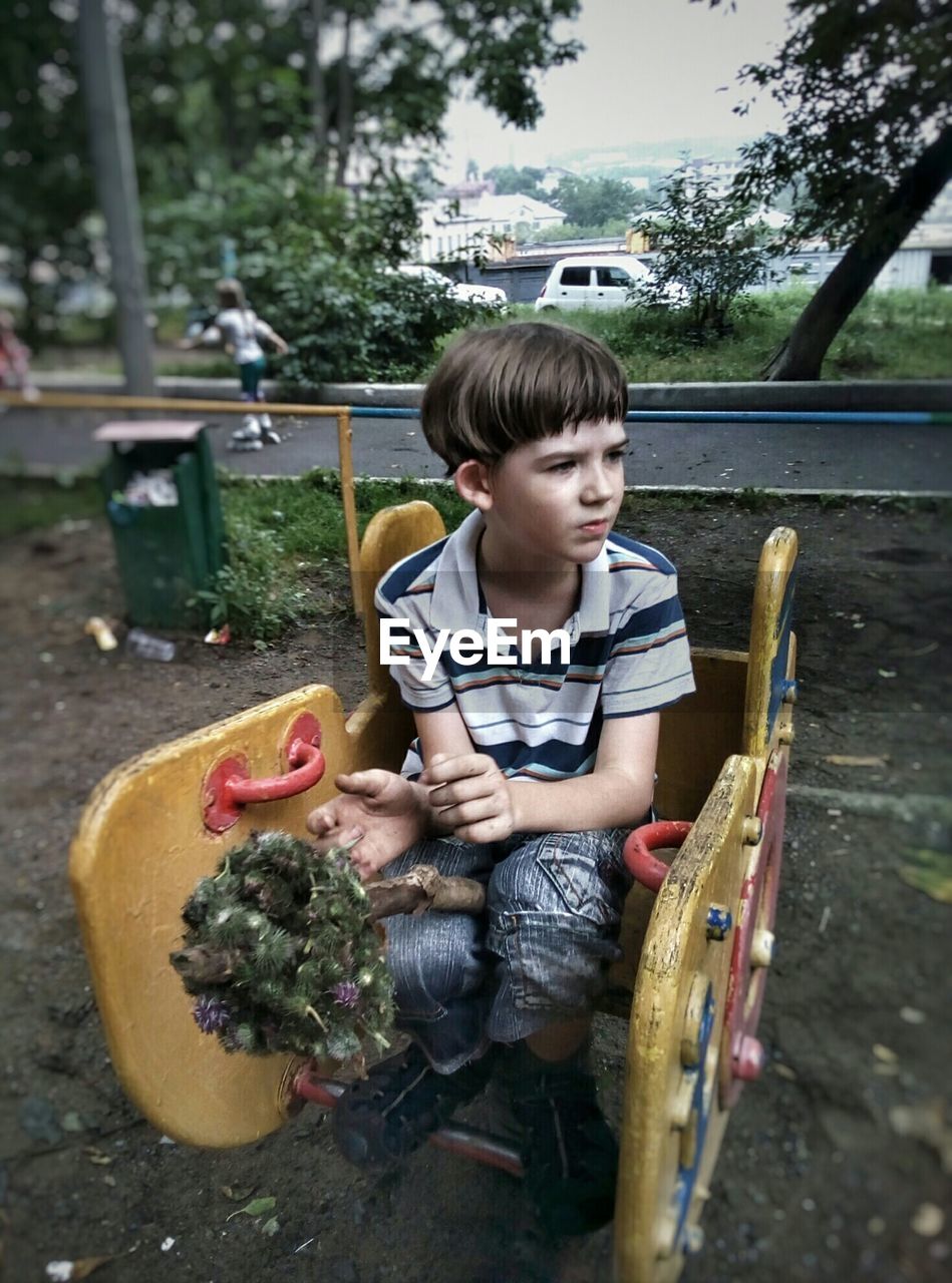 Boy sitting on outdoor playing equipment at park