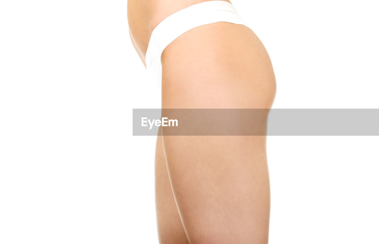 Midsection of woman in underwear while standing against white background