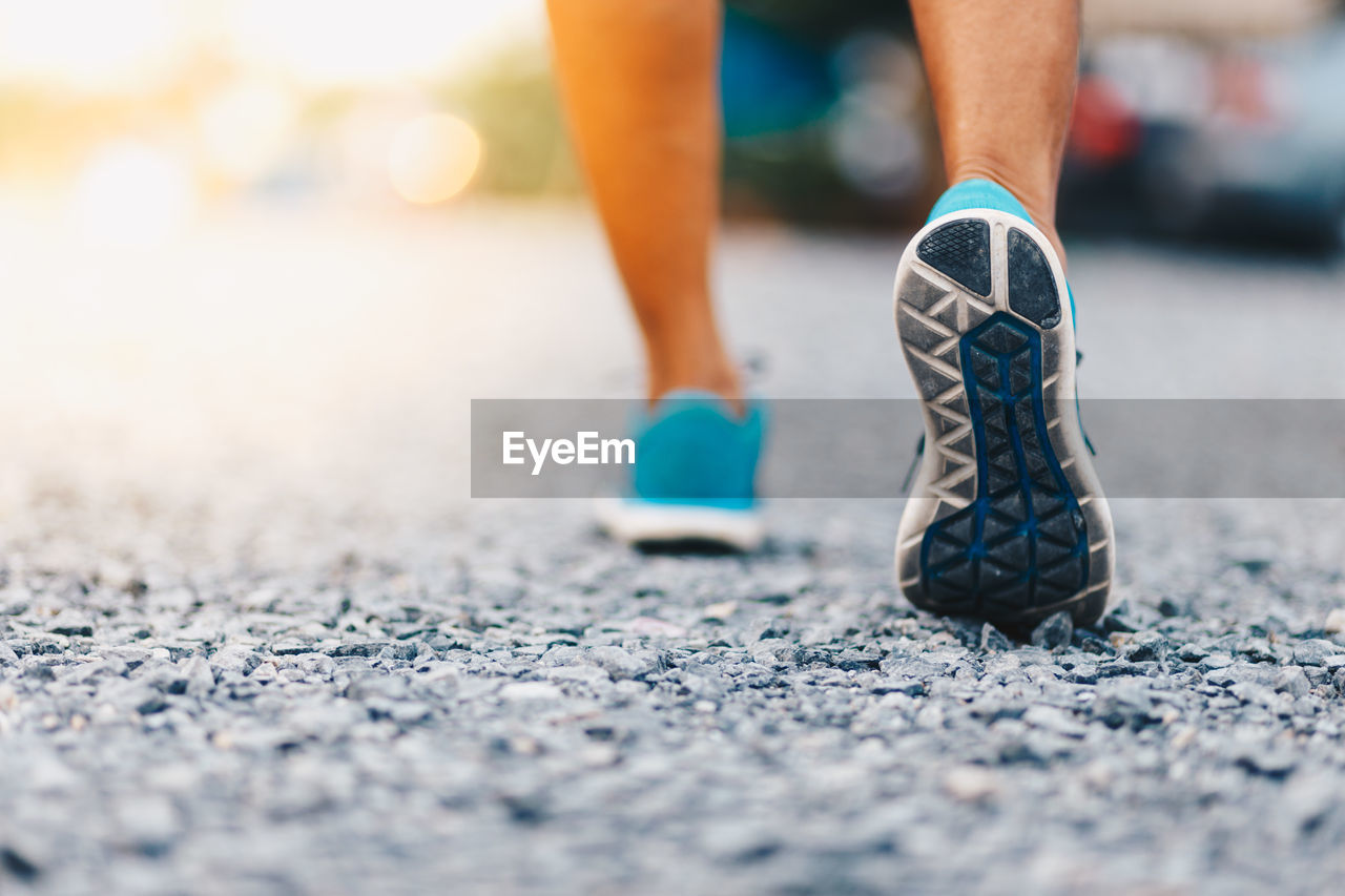 Low section of person walking on road