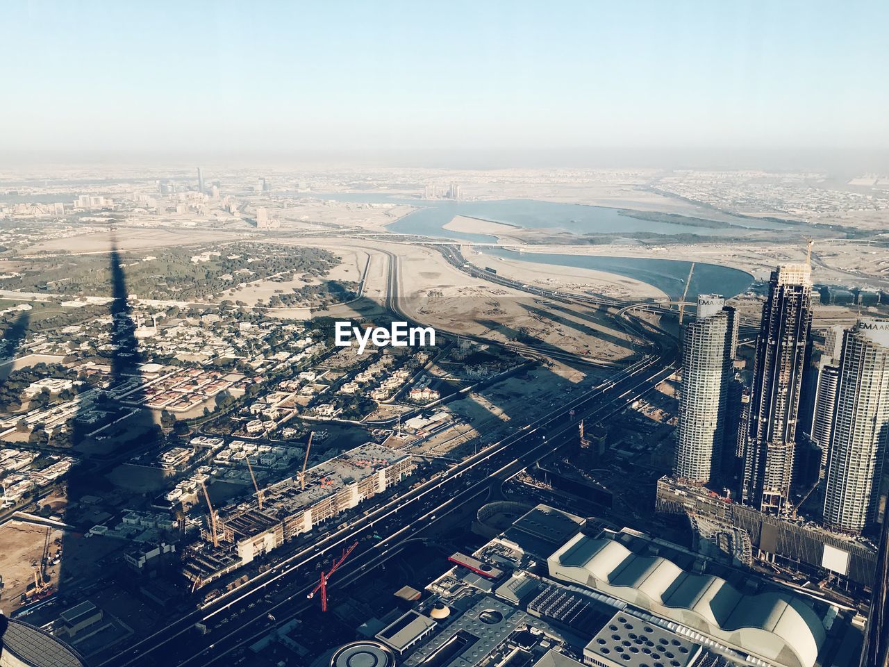 HIGH ANGLE VIEW OF BUILDINGS AND RIVER AGAINST SKY