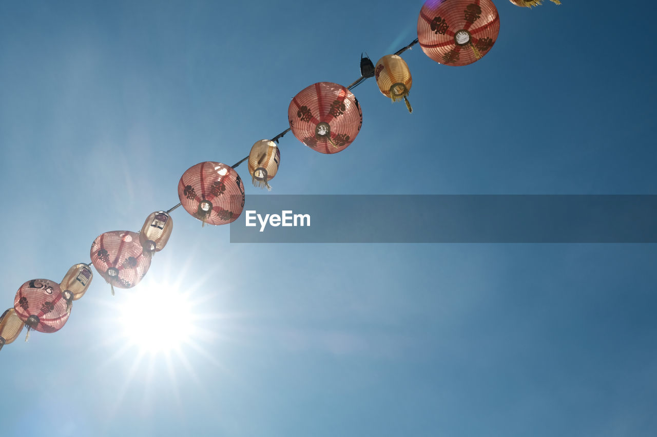 LOW ANGLE VIEW OF HANGING LIGHTS AGAINST SKY