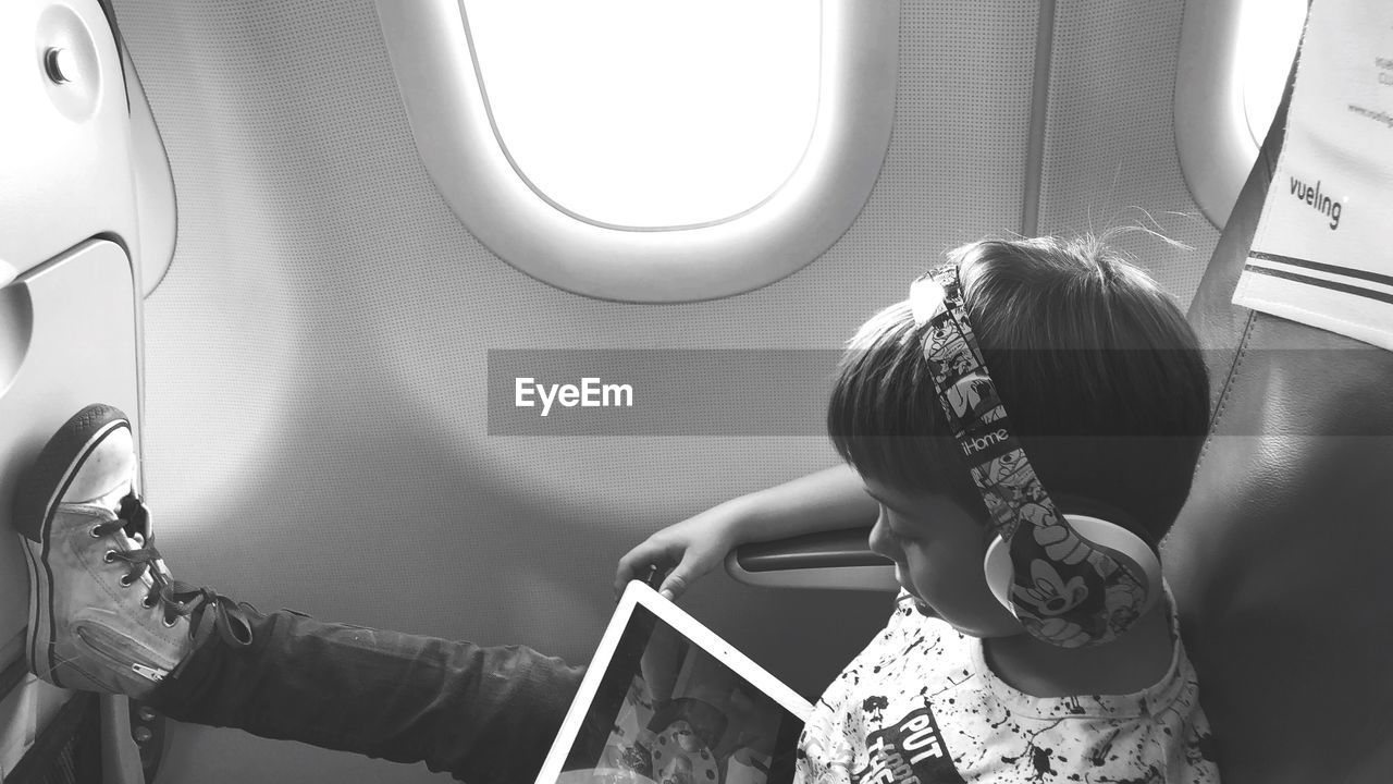 REAR VIEW OF WOMAN SITTING WITH AIRPLANE IN BUS