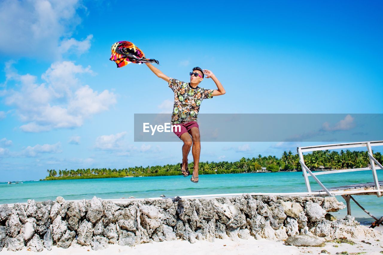 Man jumping at sea pool against sky