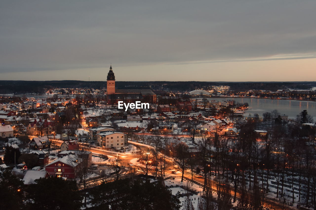 Aerial view of snow covered cityscape against cloudy sky during sunset