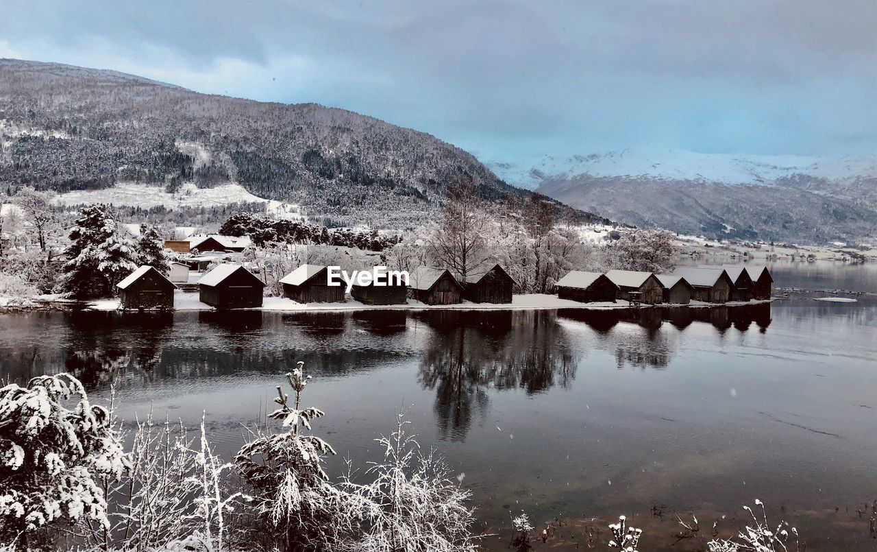 winter, water, snow, mountain, reflection, lake, scenics - nature, nature, landscape, cold temperature, environment, sky, beauty in nature, mountain range, architecture, no people, tranquility, morning, building, wilderness, tranquil scene, cloud, travel destinations, built structure, land, tree, outdoors, house, day, travel, ice, non-urban scene, building exterior, plant, tourism