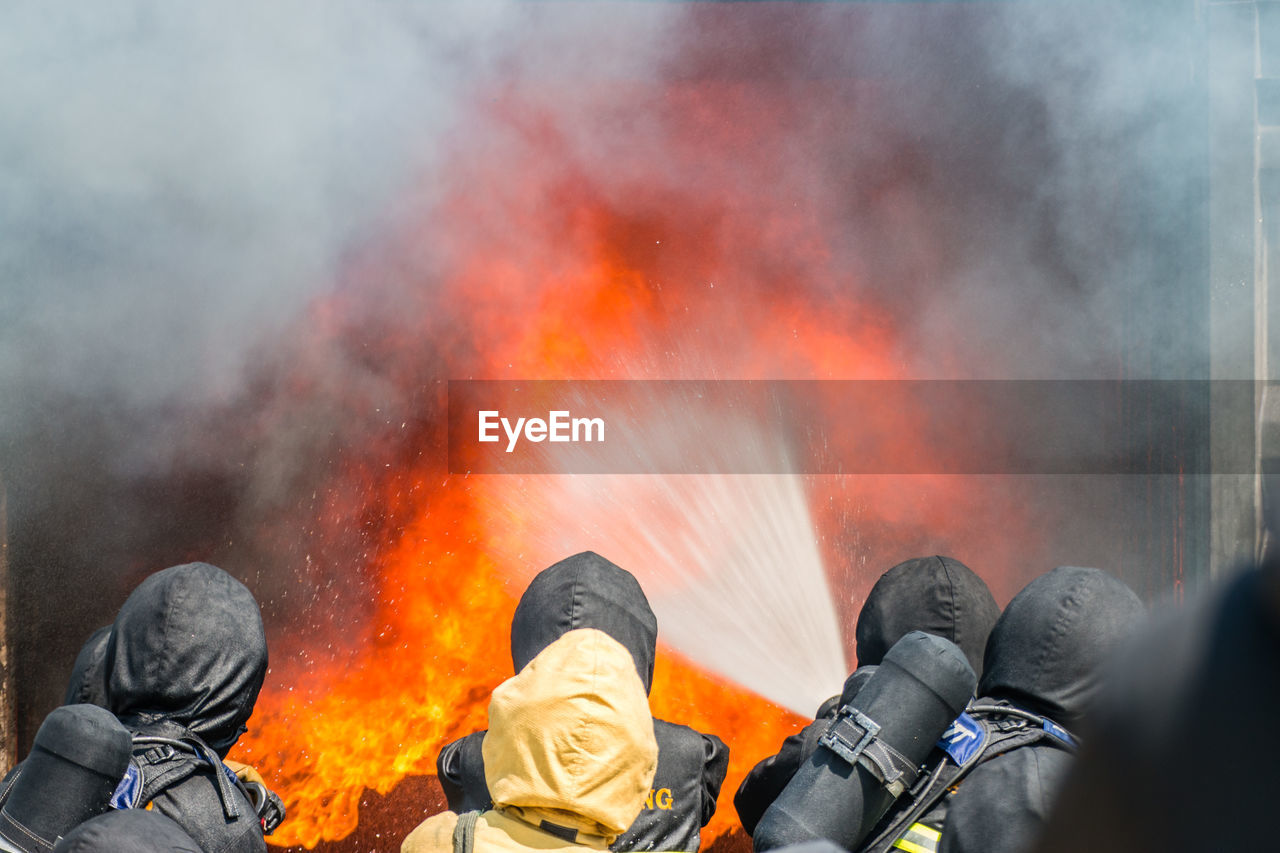 Rear view of firefighters extinguishing fire