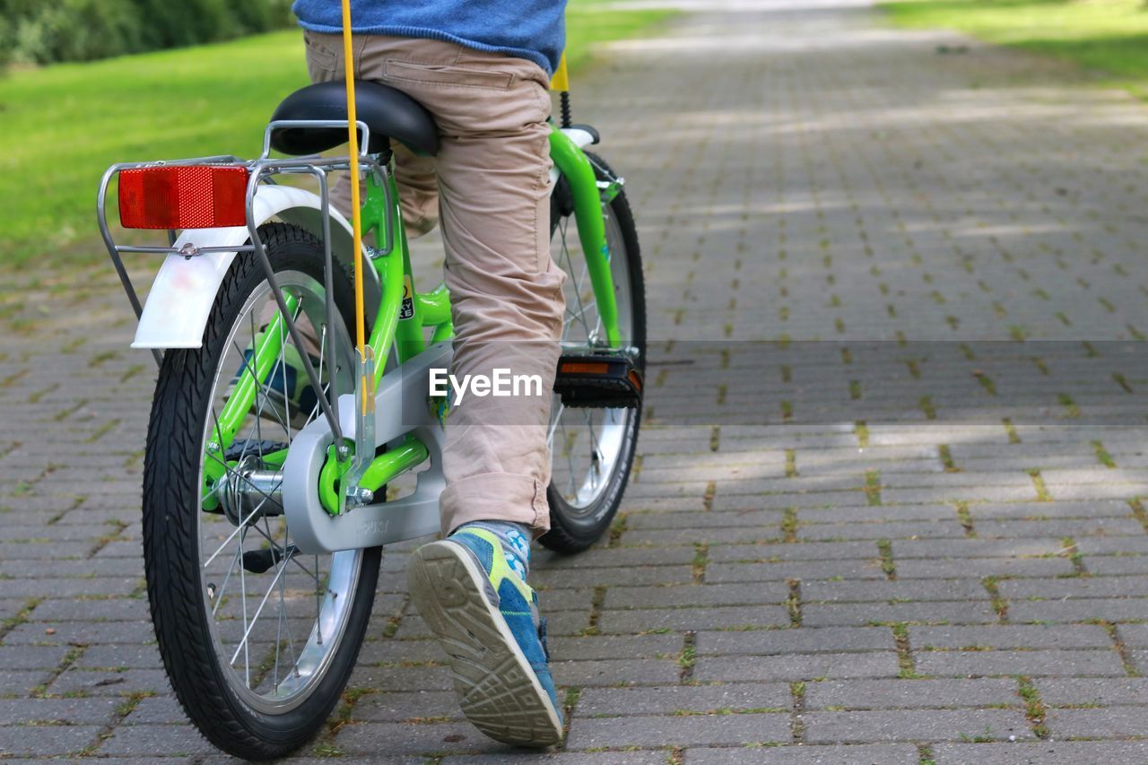 Low section of boy riding bicycle on footpath