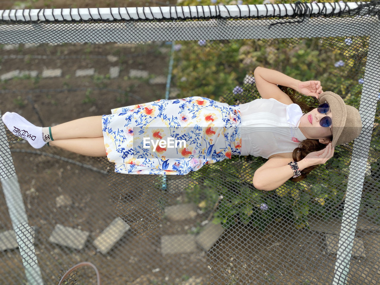 HIGH ANGLE VIEW OF WOMAN RELAXING ON FENCE