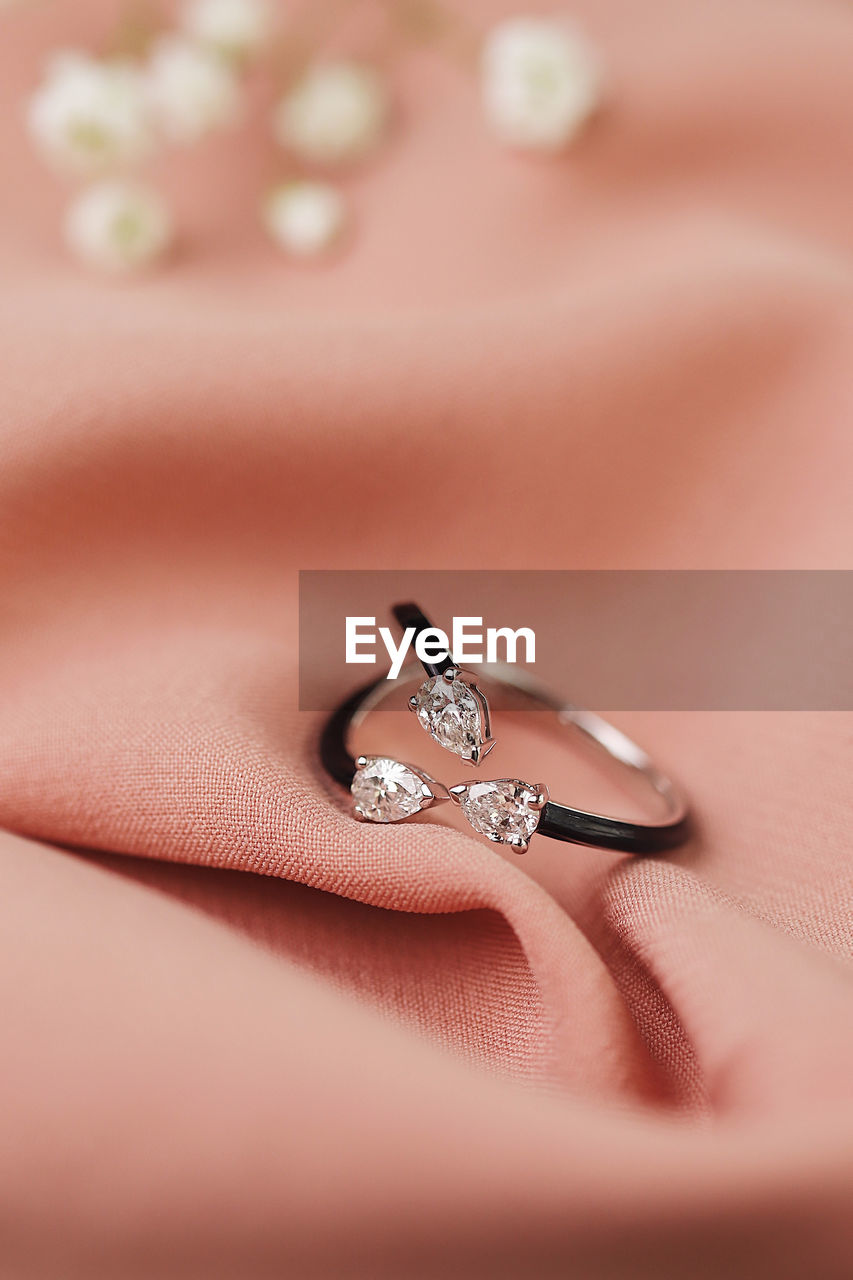 Close-up of jewelry with flowers against textile