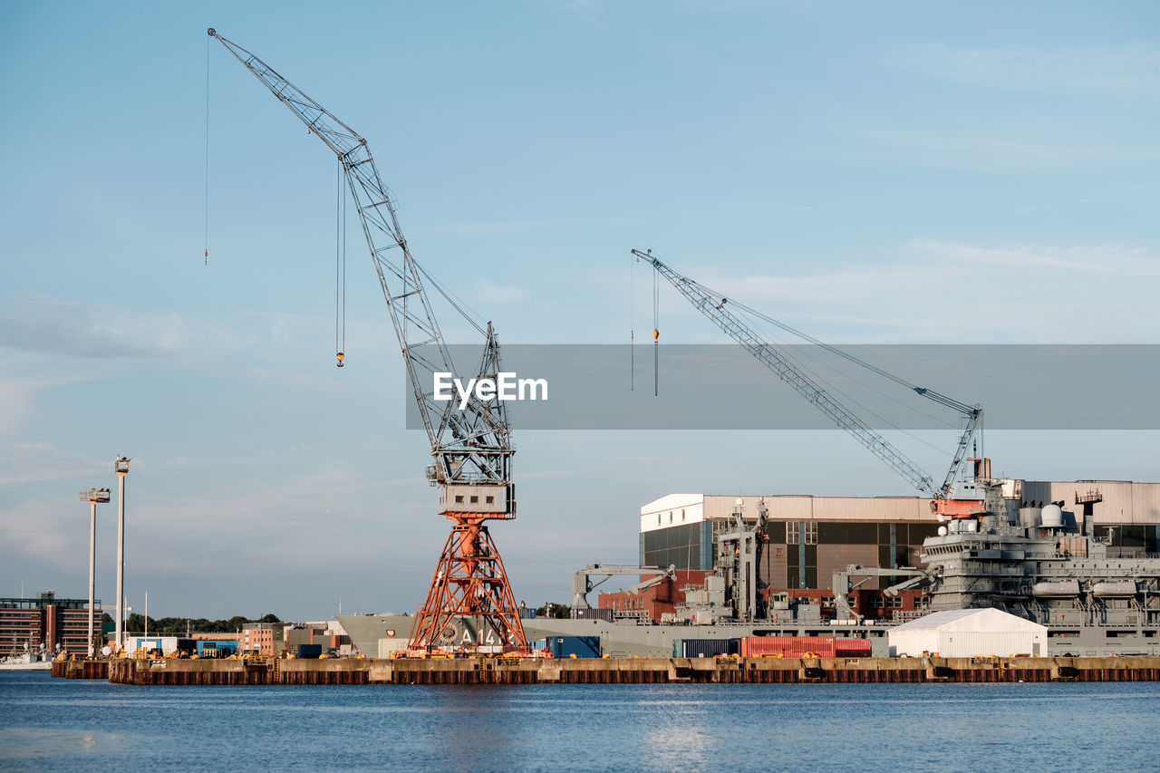 CRANES AT CONSTRUCTION SITE AGAINST SKY