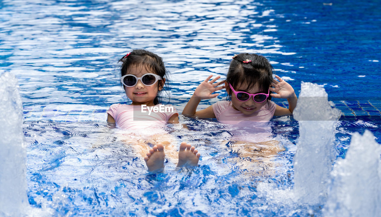 PORTRAIT OF SIBLINGS SWIMMING IN POOL