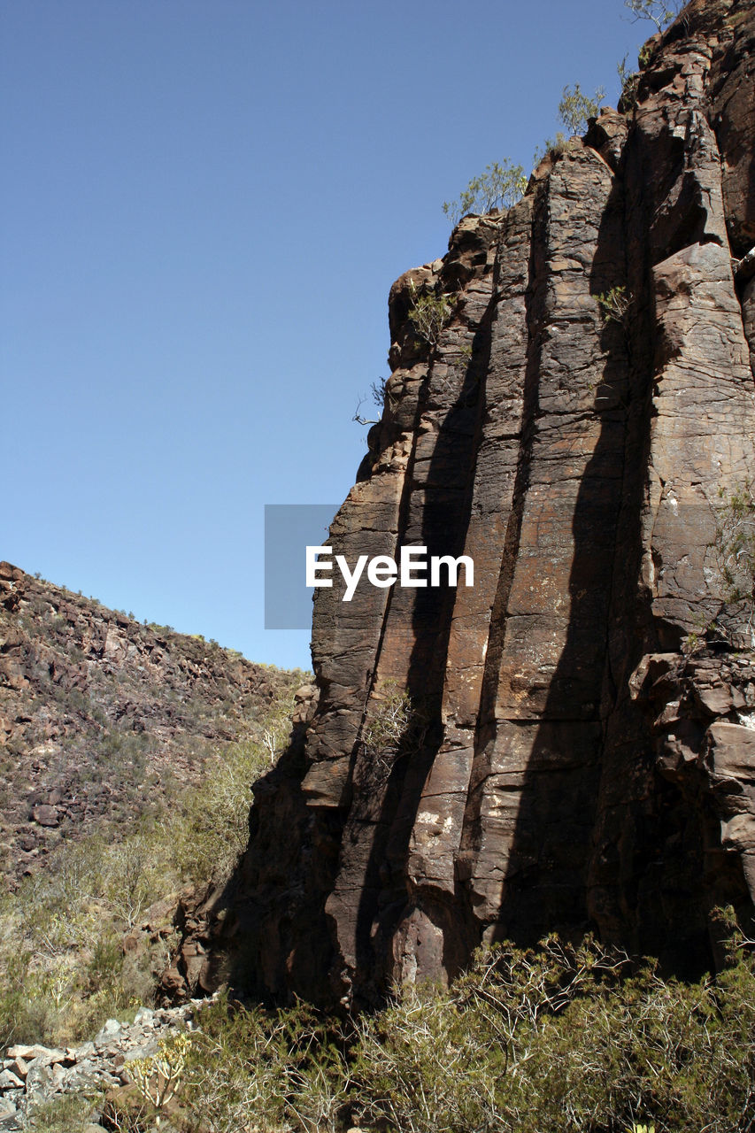 LOW ANGLE VIEW OF ROCK FORMATION ON MOUNTAIN AGAINST SKY